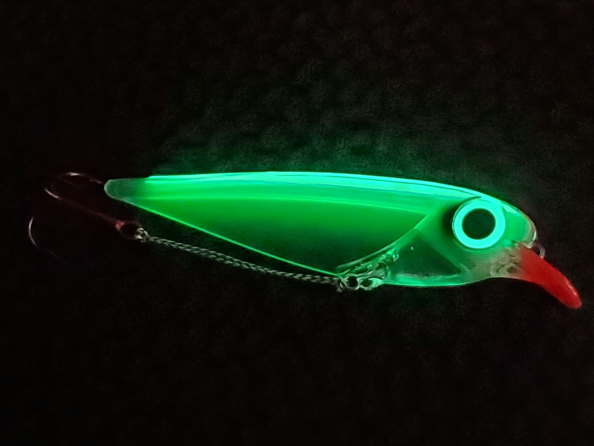 Glowing green Flatfin trolling lure on a dark background the body illuminated due to its transperency