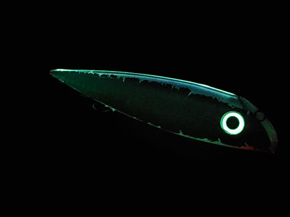 Bioluminescent fish with glowing green body and eye on a black background