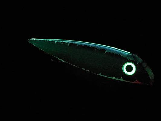 Bioluminescent fish with glowing green body and eye on a black background