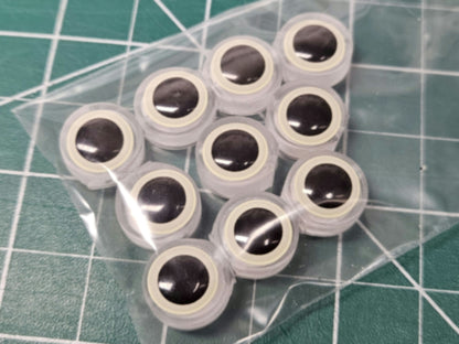 10-pack of BigEye Trolling Fly artificial eye Beads for salmon and trout. Feature large glow eyes, translucent UV resin body, and line thru-hole shown on a green work mat.