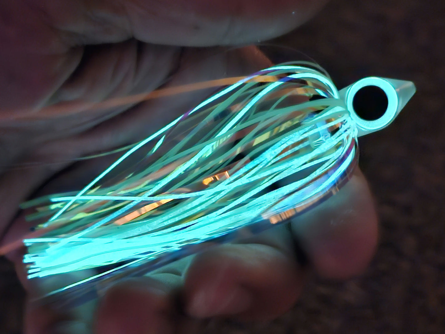 Close-up in my hand of a BigEye Trolling Fly Head tied with brightly glowing eye and silicone skirts