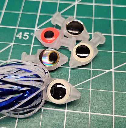 Close-up of 5 BigEye Trolling Fly Heads each with different colored eyes and unique keeper-tying collars on a green work mat.