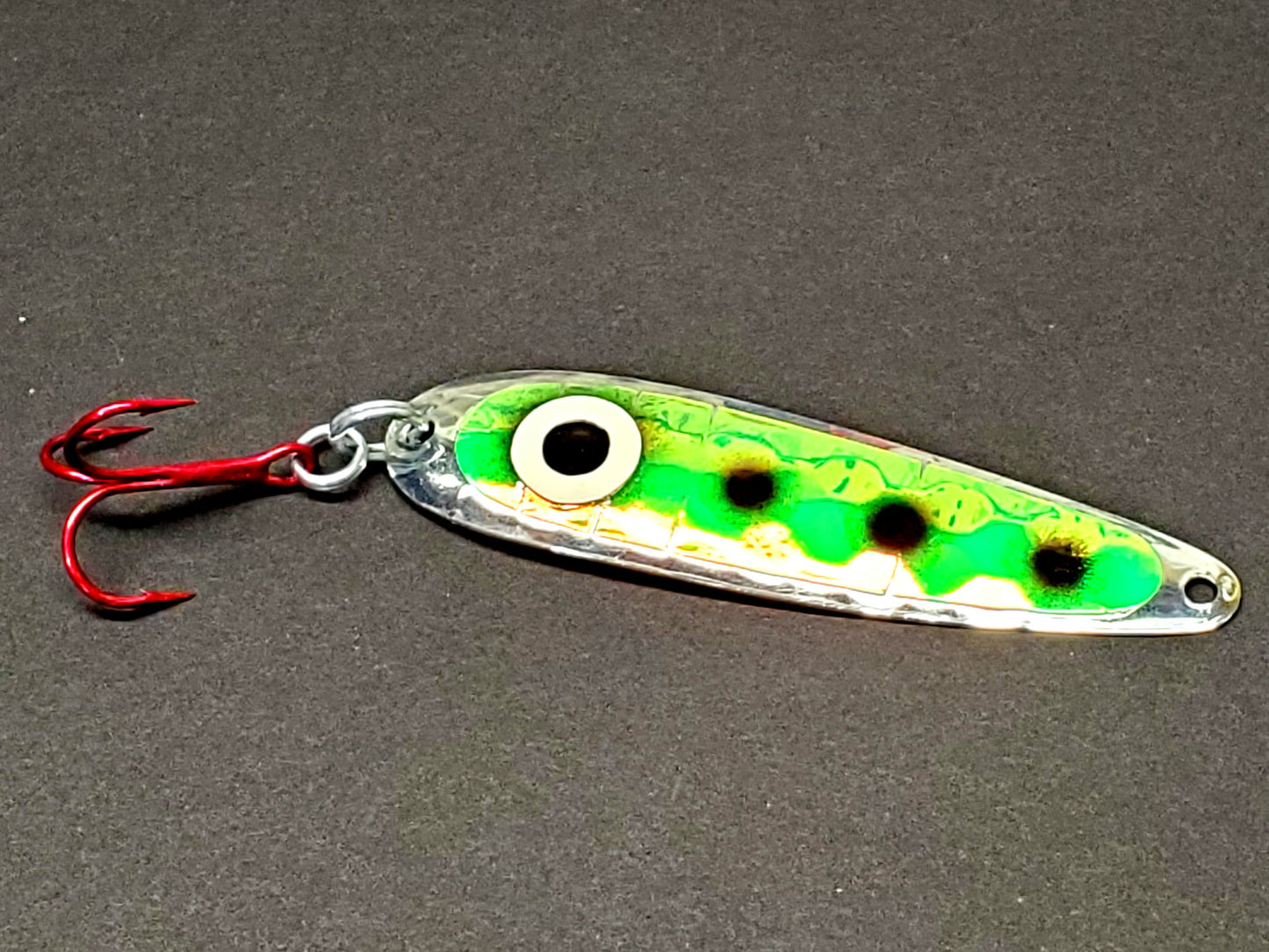 Salmon trolling spoon with a green and black pattern on a gray background