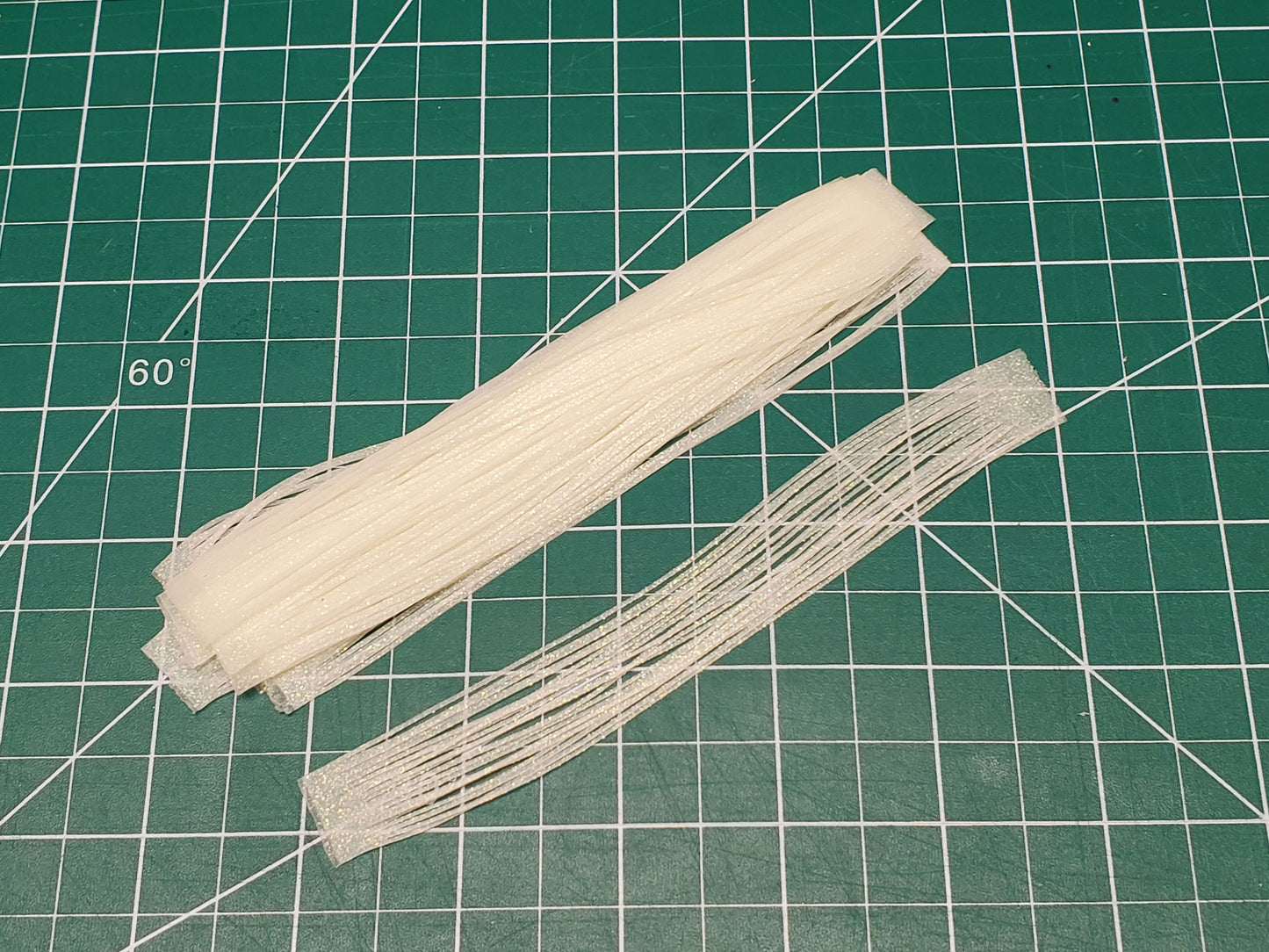 10pcs of Green glow silicone skirt tabs on work mat in daylight
