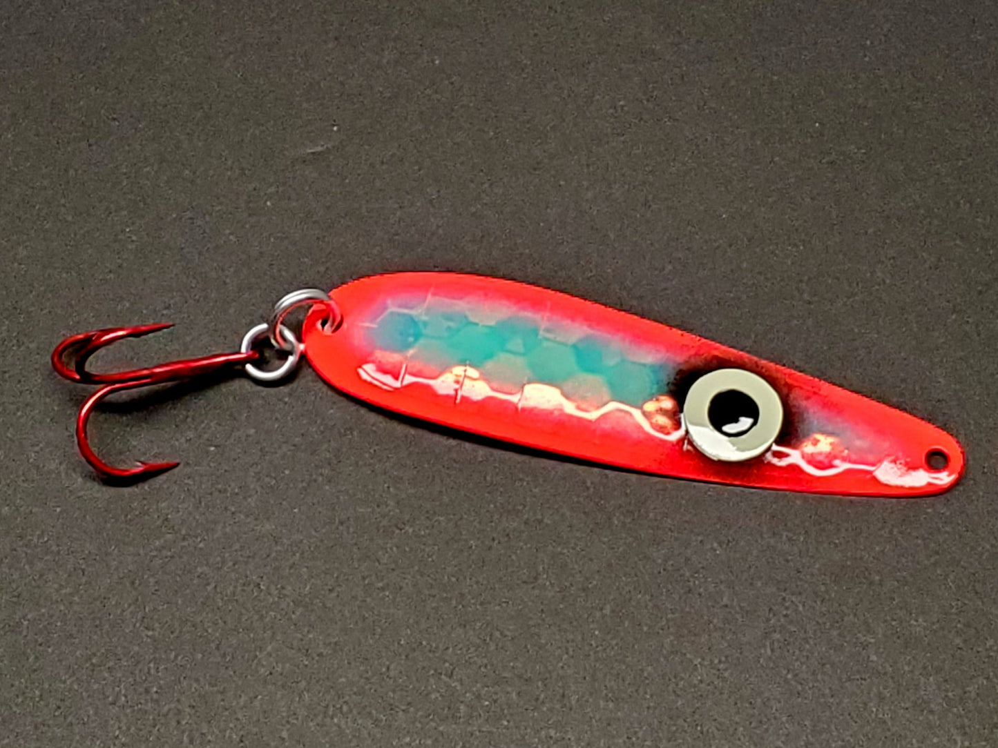 Fisher Tackle 'SeeingRed' trolling spoon with large ring eye and hot red sides on dark background