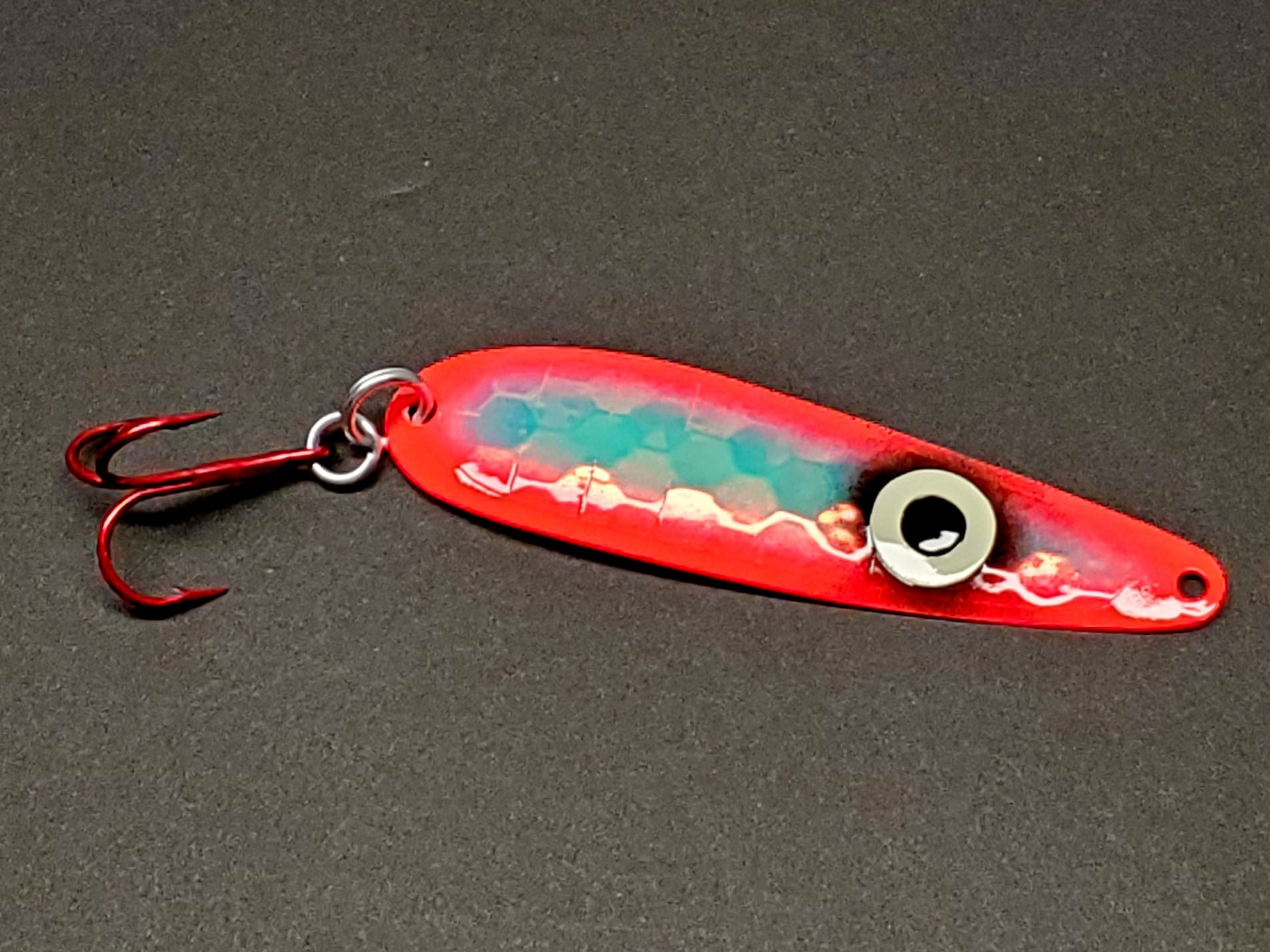 Fisher Tackle 'SeeingRed' trolling spoon with large ring eye and hot red sides on dark background