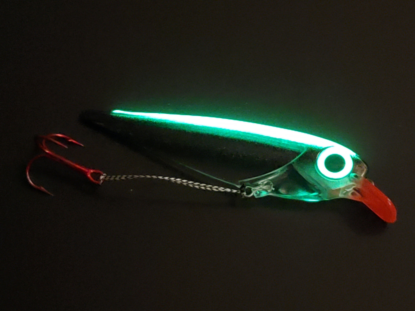 Black Striped FlatFin Trolling Lure with Red Lip and Large Glow Eye inglowing on dark background