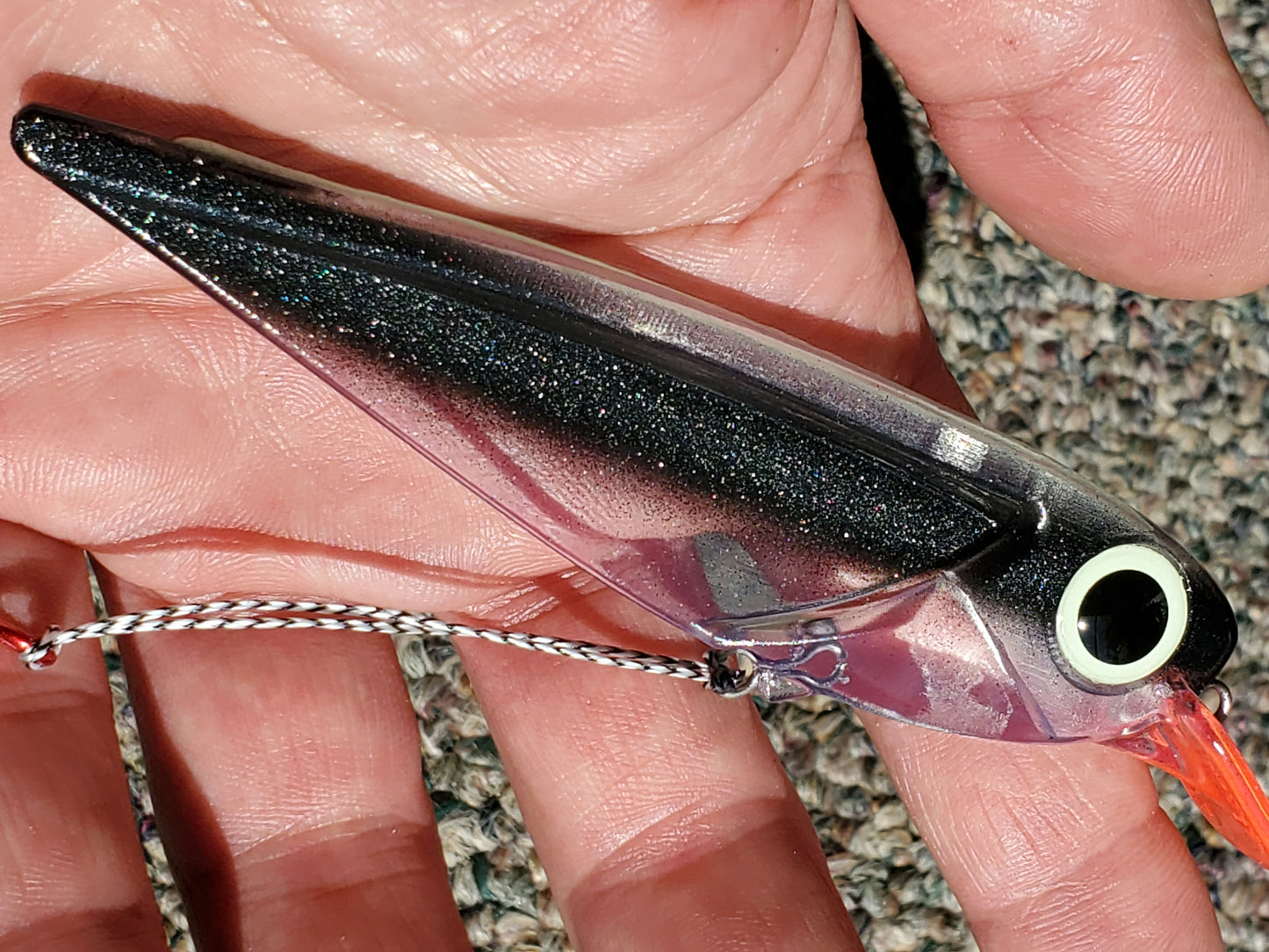 Black Striped FlatFin Trolling Lure in hand with full sun