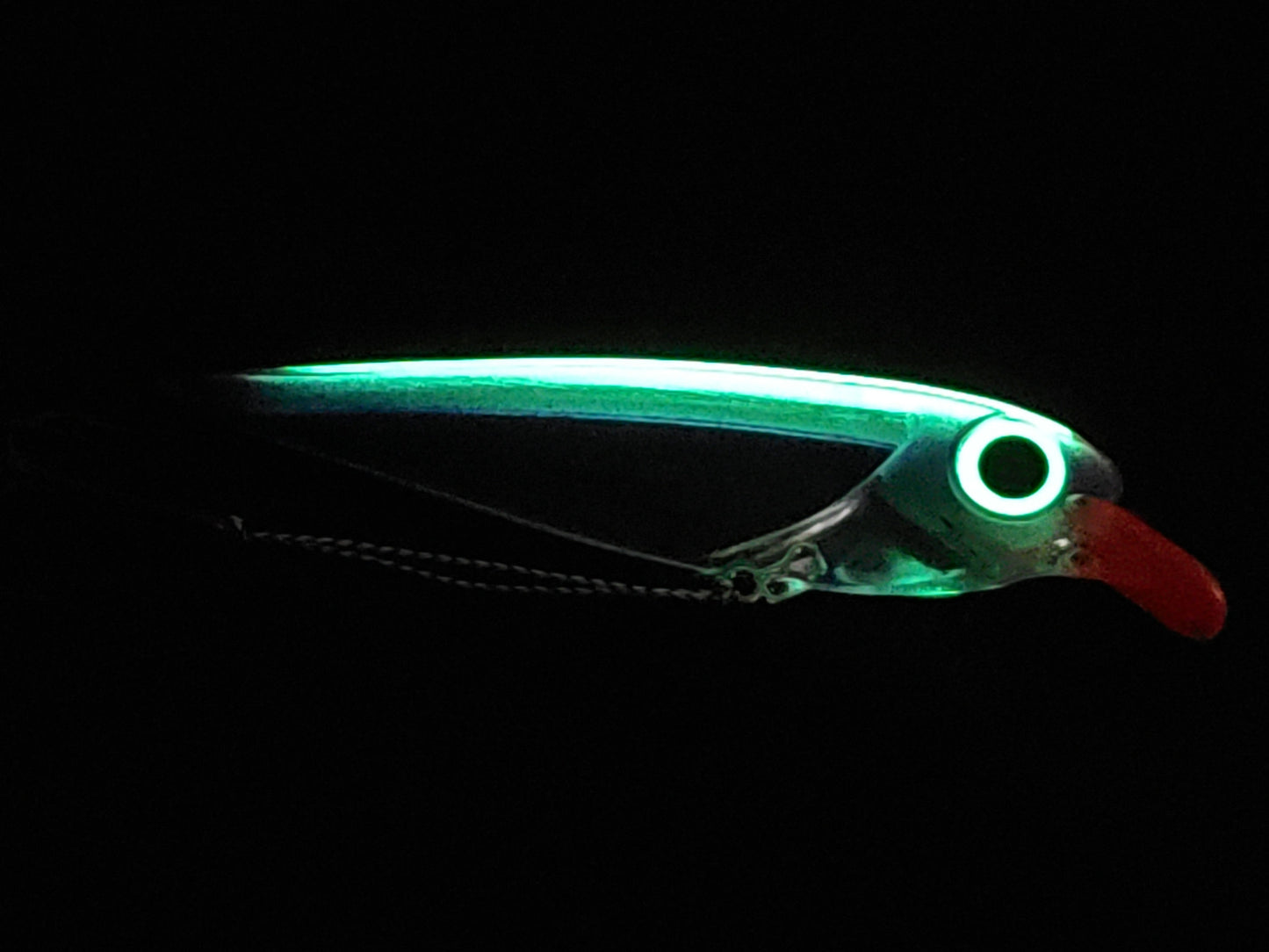 Purple FlatFin Minnow Lure on Black Pebble Background glowing in dark