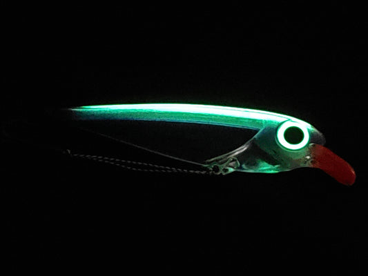 Purple FlatFin Minnow Lure on Black Pebble Background glowing in dark