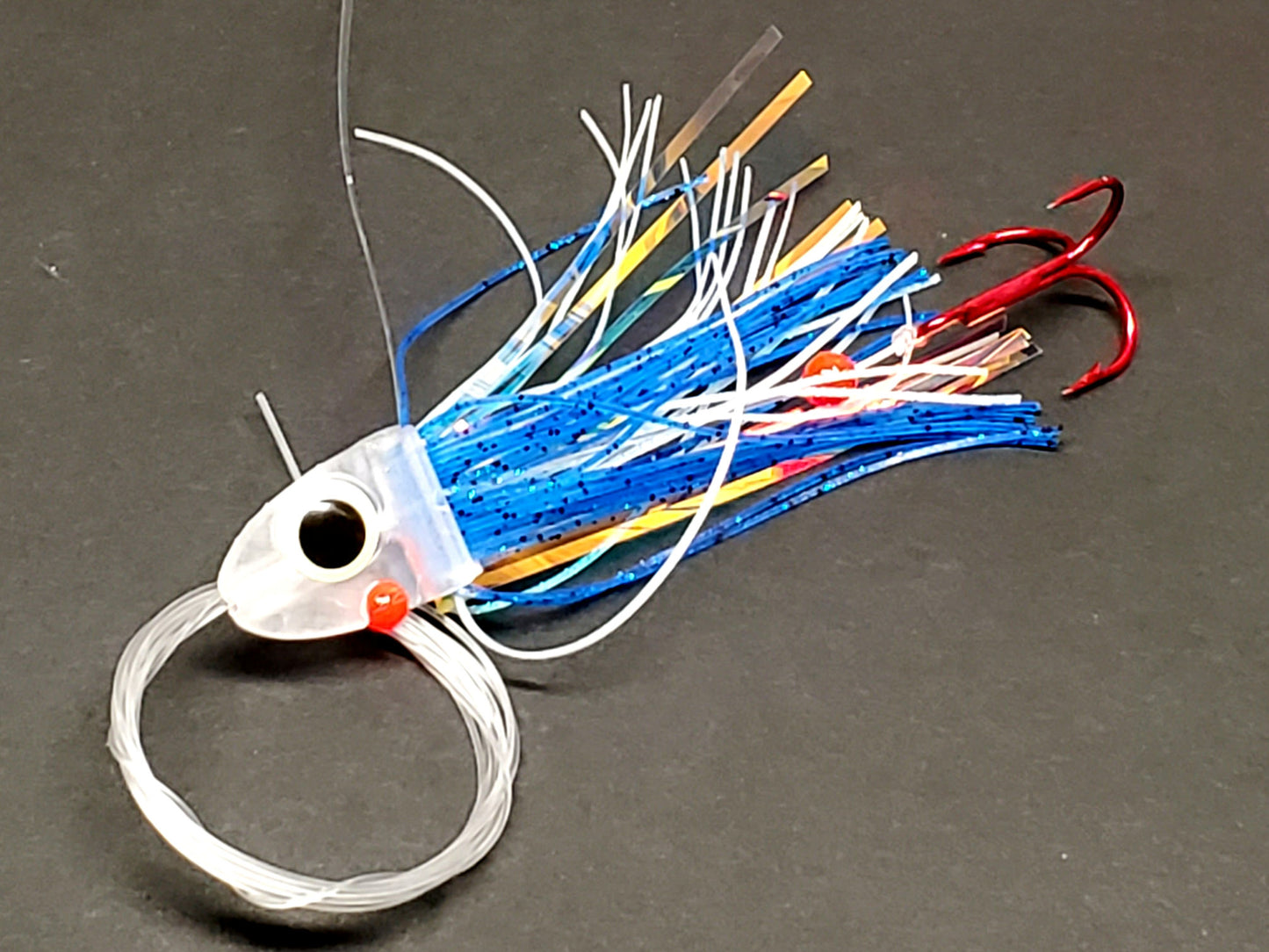 Salmon trolling fly with  blue skirting and large glow eye on a gray background
