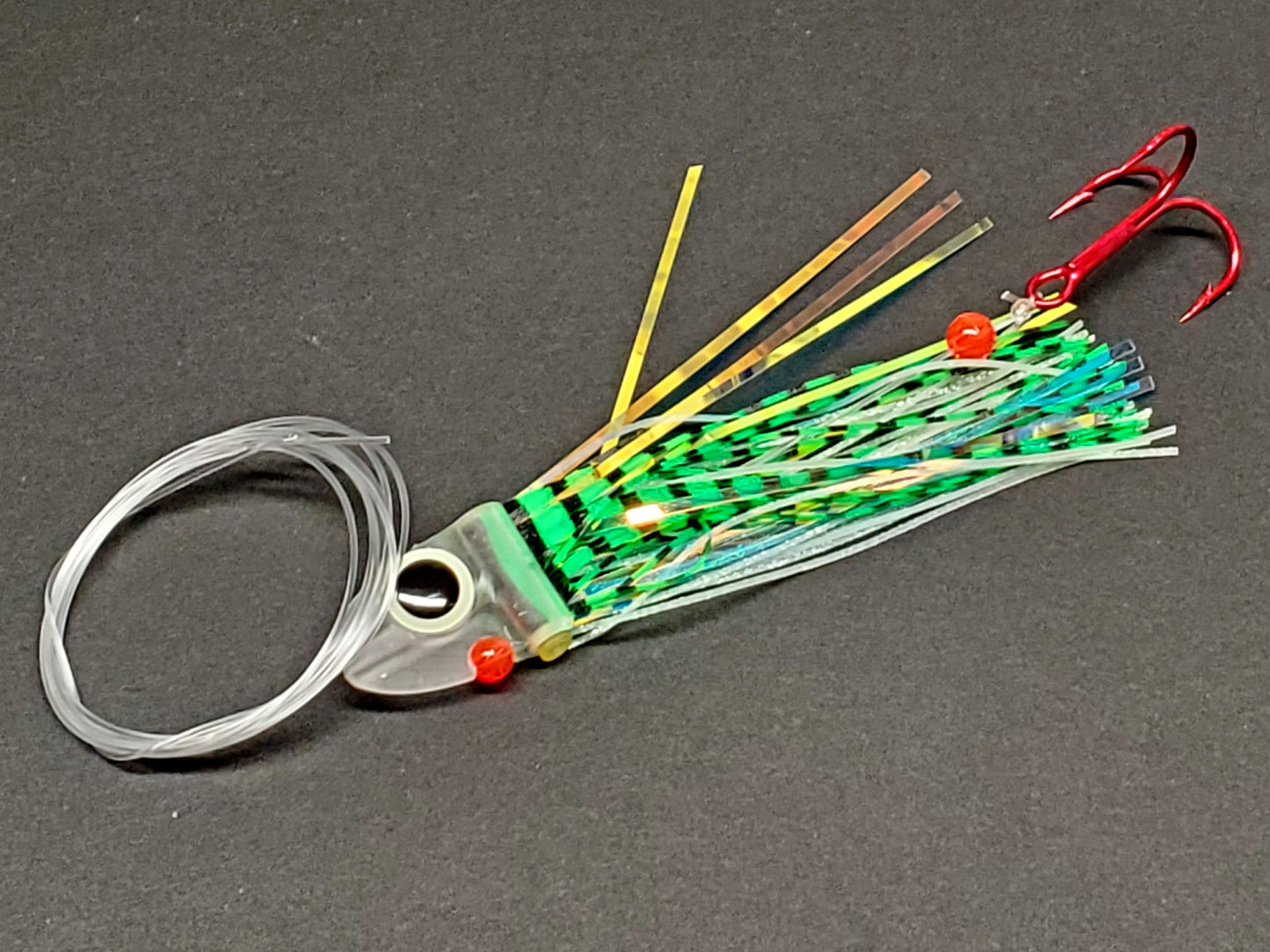 Salmon trolling fly with  green tiger striped black and red details on a gray background