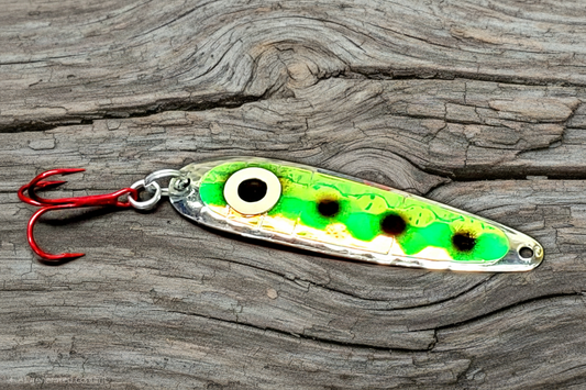 Salmon trolling spoon with a green and black pattern on weathered wood background