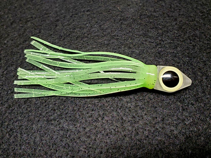 Green squid fishing lure with a black eye on a dark background