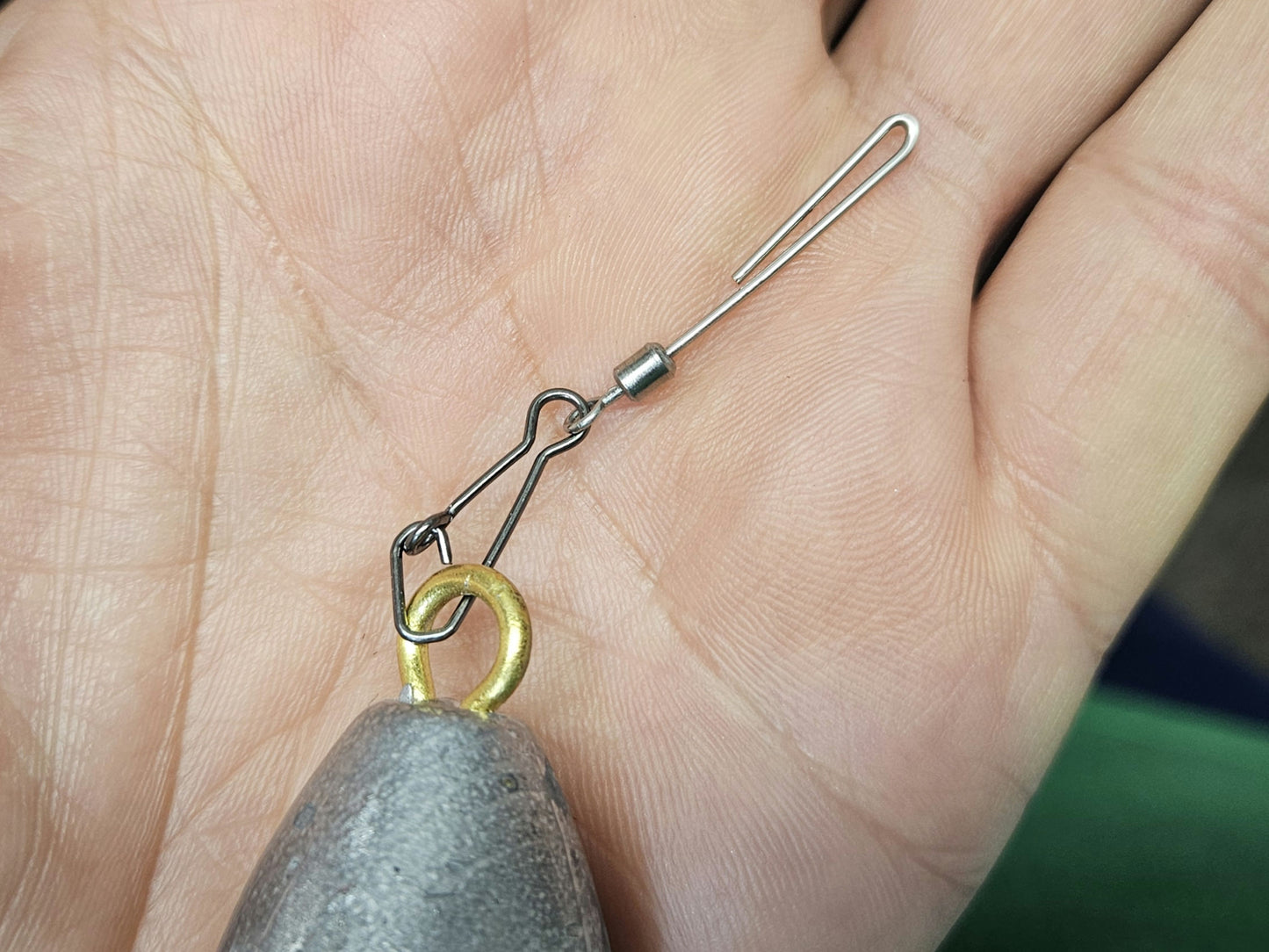 close-up of cannonball hanger clipped to actual lead weight in palm of hand
