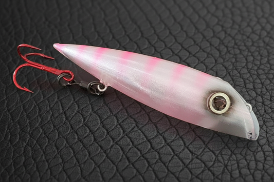FishGunn Salmon Plug 'Tizzy Fit' in daylight against black scaled leather background showing lures pearlescent white glitter sides, large glow eye and hot pink ladder back stripes