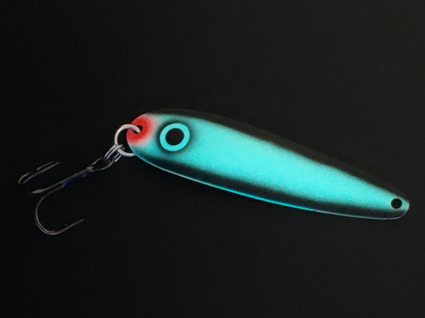Fisher Tackle UltraMega Glow 'Black Gunnship' salmon trolling spoon with teal glow base, a large black eye and black sides glowing in dark